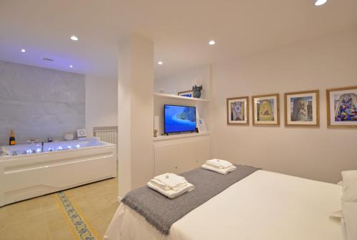 卡塔尼亚7 BLU Casa vacanze con idromassaggio的一间卧室配有一张床、一个浴缸和一台电视。