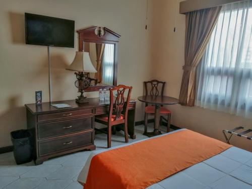 危地马拉皇宫酒店的一间卧室配有书桌、桌子和床。