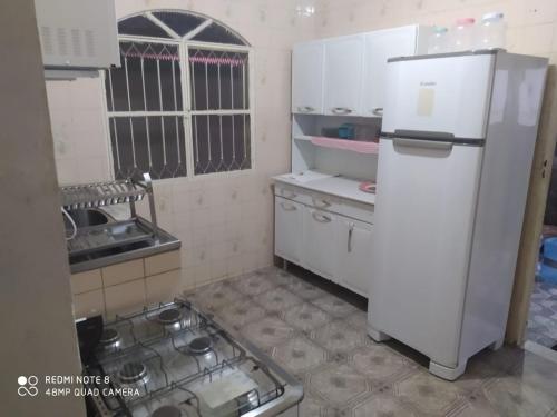 伊塔蒂亚亚Casa 3 quartos com Piscina em Itatiaia的厨房配有白色冰箱和炉灶。