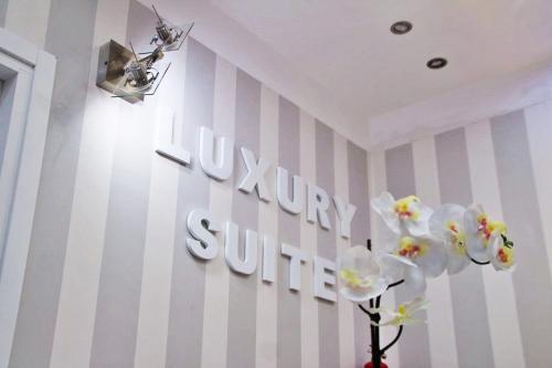 佩斯卡拉B&B Pescara Centro Luxury Suite的花瓶里花的墙上的标志