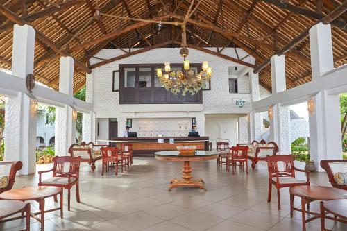 迪亚尼海滩蓝花楹印度洋海滩度假村的大型客房配有桌椅和吊灯。