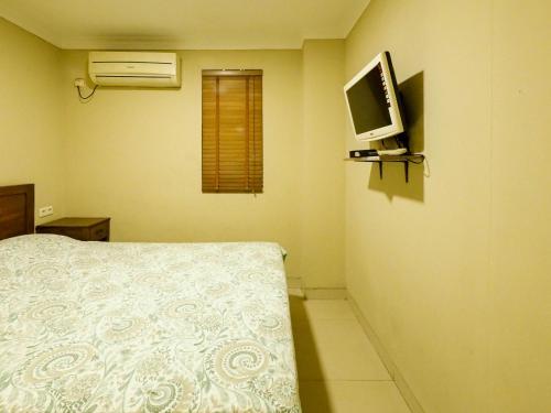 雅加达Rhiz Guest House Tebet的卧室配有一张床,墙上配有电视。