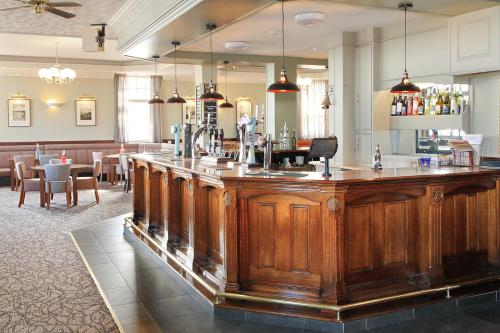 哈特尔普尔航海酒店的餐厅的木制大酒吧,配有桌子