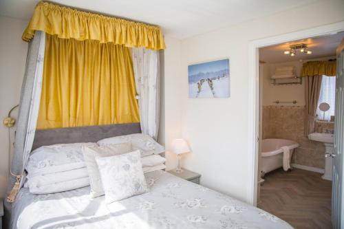 凯特尔韦尔The Cottage Tea Room B&B的卧室配有白色的床和黄色窗户。
