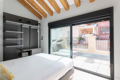 阿利坎特Arenal Suites Alicante的一间卧室设有一张床和一个大型玻璃窗