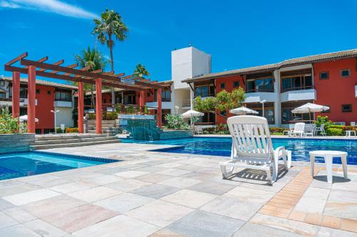 塞古罗港波尔图瑙斯普拉艾酒店的一座游泳池,旁边是一座建筑,配有椅子