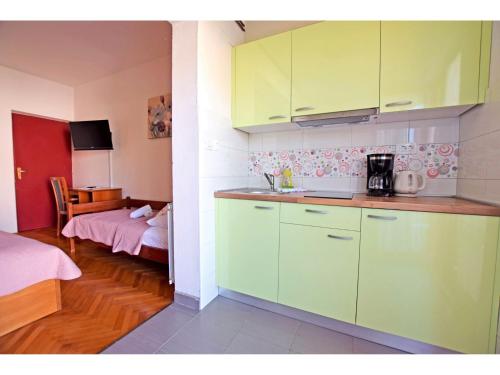 斯塔利格拉德-帕克利尼卡Apartments in Starigrad-Paklenica 33853的一个带绿色橱柜的厨房和一间带一张床的房间