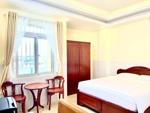 芹苴Khách sạn Long Hà的卧室配有一张床和一张桌子及椅子