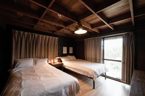 恩纳LOGIN OKINAWA -wood-的一间卧室设有两张床和窗户。