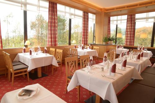 比绍夫斯格林凯瑟奥姆酒店的餐厅设有白色的桌椅和窗户。