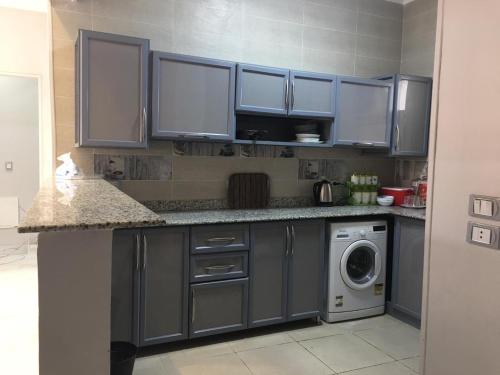 开罗Ramco For Furnished Apartments And Accommodation Compound Leila的厨房配有蓝色橱柜和洗衣机。