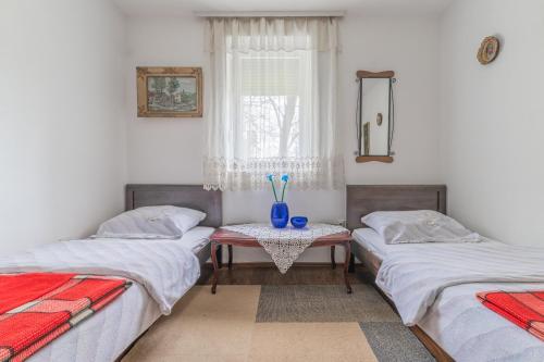 尼克希奇Frile Apartments的一间设有三张床的房间和一张桌子,上面有花瓶