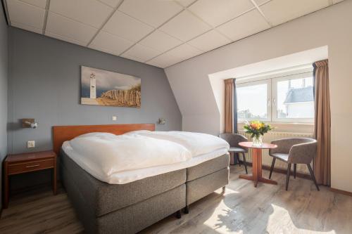 海滨诺德韦克明星酒店的一间卧室配有一张床、一张桌子和一个窗户。