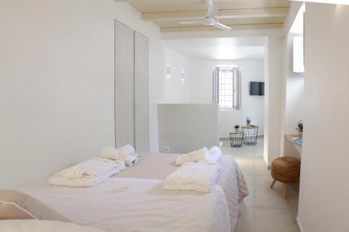 伊兹拉La Maison de Marie Geraldine的白色卧室配有白色床单和毛巾。