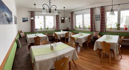 拉姆绍达赫斯坦哈斯雷乃霍夫农家乐的餐厅设有白色的桌椅和窗户。