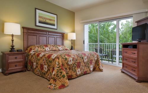 欧塞奇比奇奥沙克湖世誉酒店的一间卧室配有一张床、一台电视和一个阳台