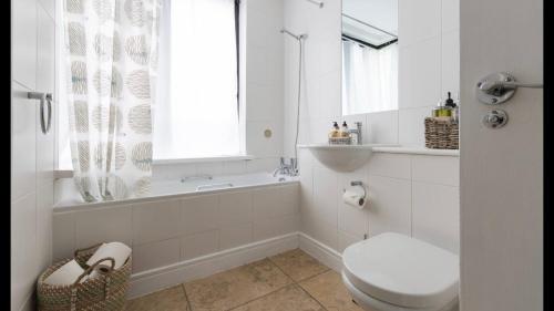 史云顿1 Farnsby Street Apartment 19的白色的浴室设有卫生间、浴缸和窗户。