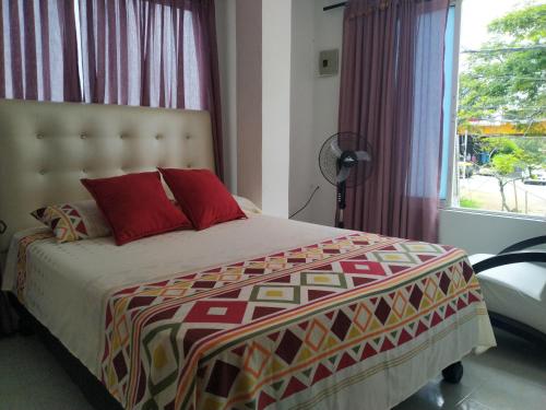 卡利Apartamento oasis del norte的一间卧室配有一张带红色枕头的床和一扇窗户
