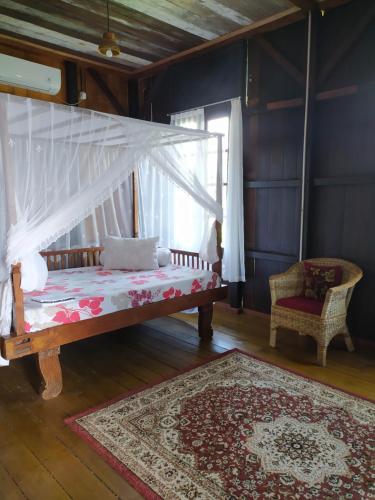 TanjungbingaRock and Wreck Dive Resort的一间卧室配有一张带天蓬和地毯的床