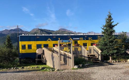 希利德纳利百乐酒店的一辆黄色和蓝色的火车车厢,后面有群山
