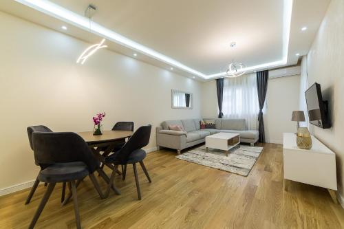 波德戈里察Apartments Centrale 28的客厅配有桌椅和沙发