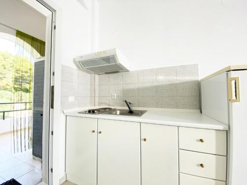 波塞蒂Posidi Studios的厨房配有白色橱柜和水槽