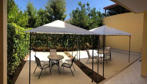 莱切B&B SALento Garden的庭院里配有两张桌子和椅子以及遮阳伞