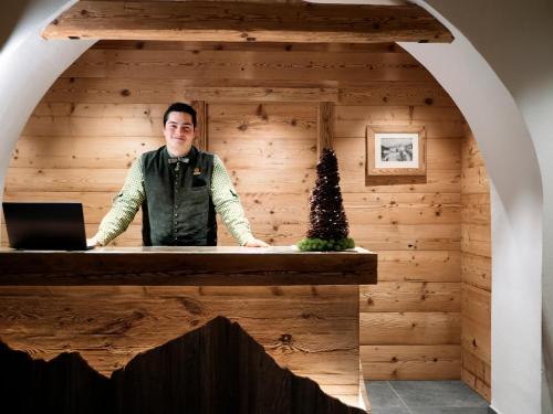 圣维托-迪卡多雷FIORI Dolomites Experience Hotel的站在木房子桌子上的男人