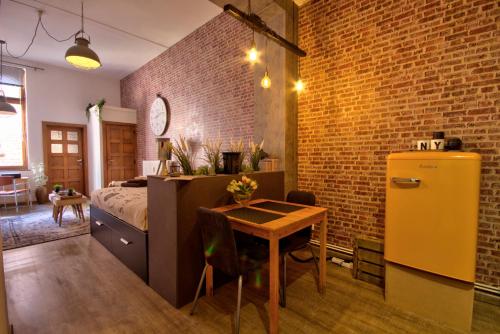那慕尔New York Loft - Fully equipped and available long-term - Perfect location IN city center的一间卧室配有一张床铺、一张桌子和一台冰箱