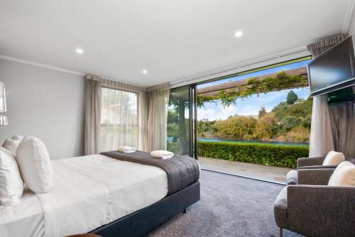 陶波River View Retreat - Taupo的一间卧室设有一张床和一个大窗户