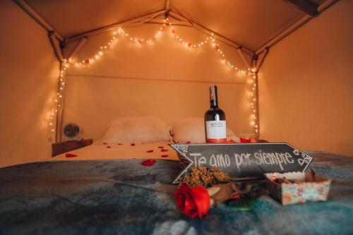 塔比奥Glamping rio frio Tabio的一张带一瓶葡萄酒和招牌的床