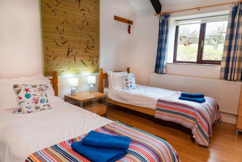 博斯卡斯尔Polrunny Farm Elderberry Cottage with sea view的客房设有两张床和窗户。