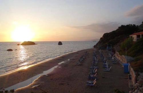 圣马太奥斯Stefanias Prasoudi Beach的海滩,沙滩上摆放着椅子,日落时分还有大海