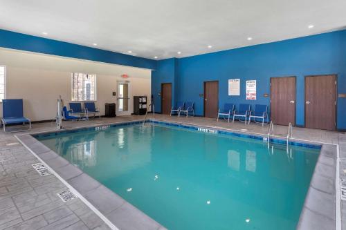尤利斯Comfort Inn & Suites Euless DFW West的一个带蓝色墙壁和椅子的大型游泳池