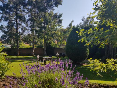 牛津Linton Lodge a BW Signature Collection Hotel的种有紫色花草、桌子和树木的花园