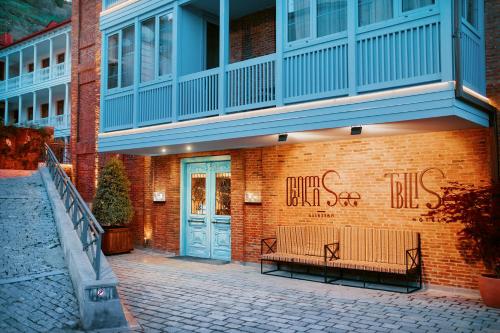 第比利斯TbiliSee Hotel的砖砌的建筑,前面有长凳,上面涂有涂鸦