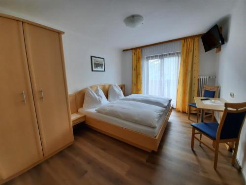 萨尔巴赫Pension Aberger的一间卧室配有一张床、一张桌子和一个窗户。