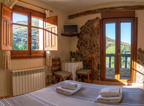 圭哈尔谢拉Hotel Rural Fuente La Teja的卧室配有床、桌子和窗户。