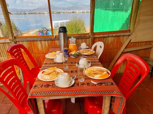 普诺Uros Lodge Lover Titiqaqa的一张桌子,上面放着食物盘,上面放着红色椅子