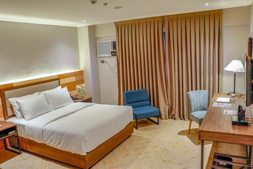 巴科洛德Acacia Hotel Bacolod的一间卧室配有一张床、一张桌子和一把蓝椅