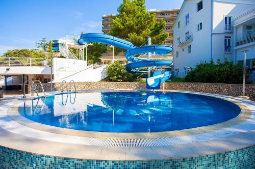 克尔克Villa Tamaris - Hotel Resort Dražica的一个带蓝色水滑梯的游泳池
