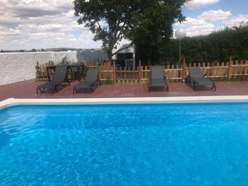 下卡尔瓦拉萨Chalet piscina privada Salamanca的水边的游泳池配有椅子和桌子
