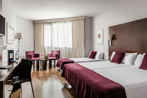 哈卡Eurostars Reina Felicia的酒店客房带两张床和一张桌子以及椅子。
