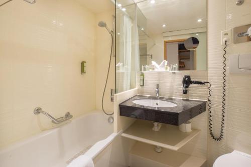 苏黎世Hotel Adler Zürich的浴室配有水槽、淋浴和浴缸。