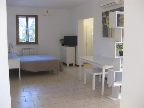 乌尔比诺Country House-B&B-Appartamenti Ai Cipressi的一间卧室配有一张床、一张桌子和一个窗户。