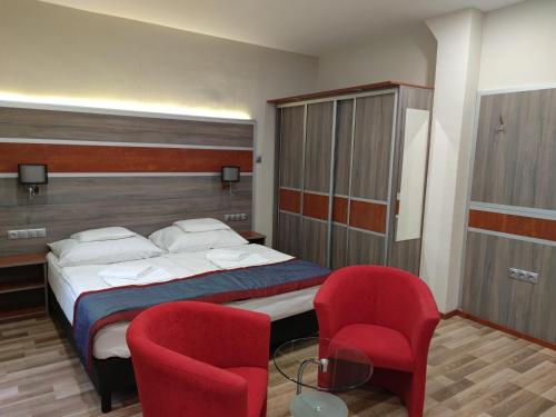 米什科尔茨道波曹弗杜那酒店的一间卧室配有一张床和两张红色椅子