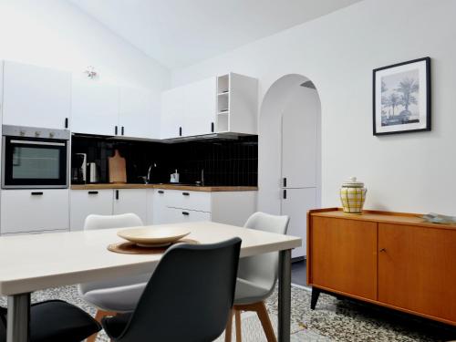 贝纳尔马德纳Palm House 10的厨房配有白色橱柜和桌椅