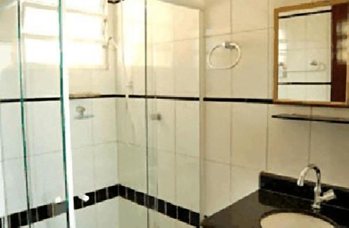 瓜鲁雅Hotel Pousada do Comendador的带淋浴、盥洗盆和镜子的浴室