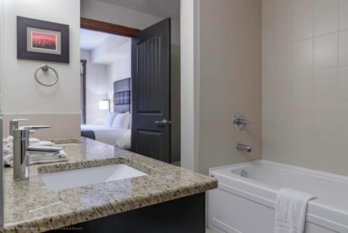 坎莫尔Stoneridge Mountain Resort的一间带水槽和浴缸的浴室以及一间带卫生间的浴室。