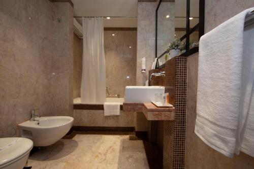 迪拜第一城堡套房酒店的浴室配有盥洗盆、卫生间和浴缸。